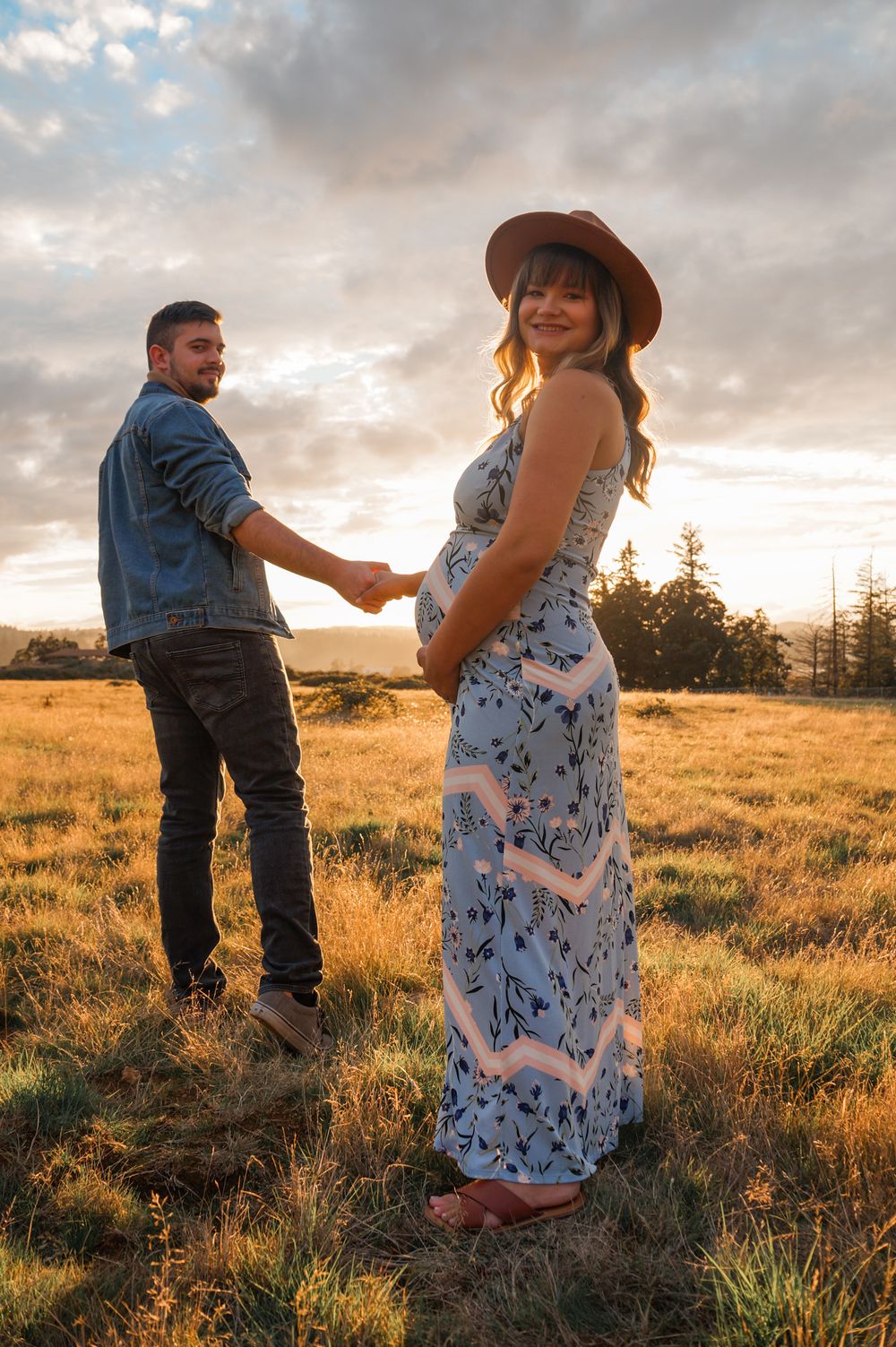 Maternity photo of couple holding hands and smiling in a natural outdoor setting in Salem OR