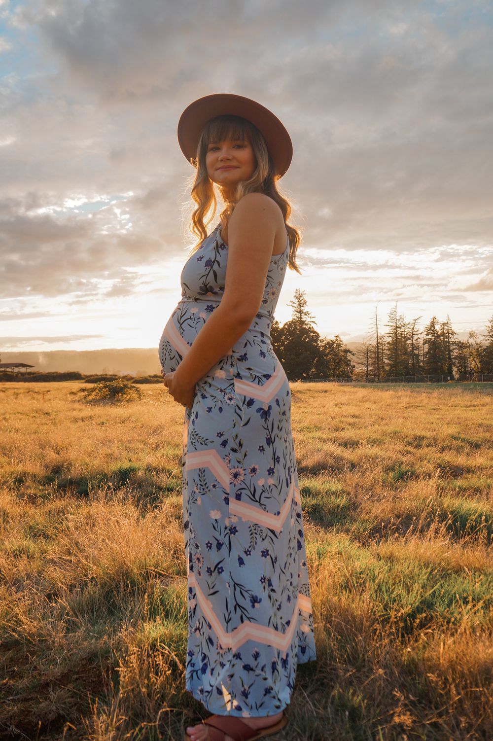 Pregnant woman standing alone in golden light during outdoor maternity session in Salem OR