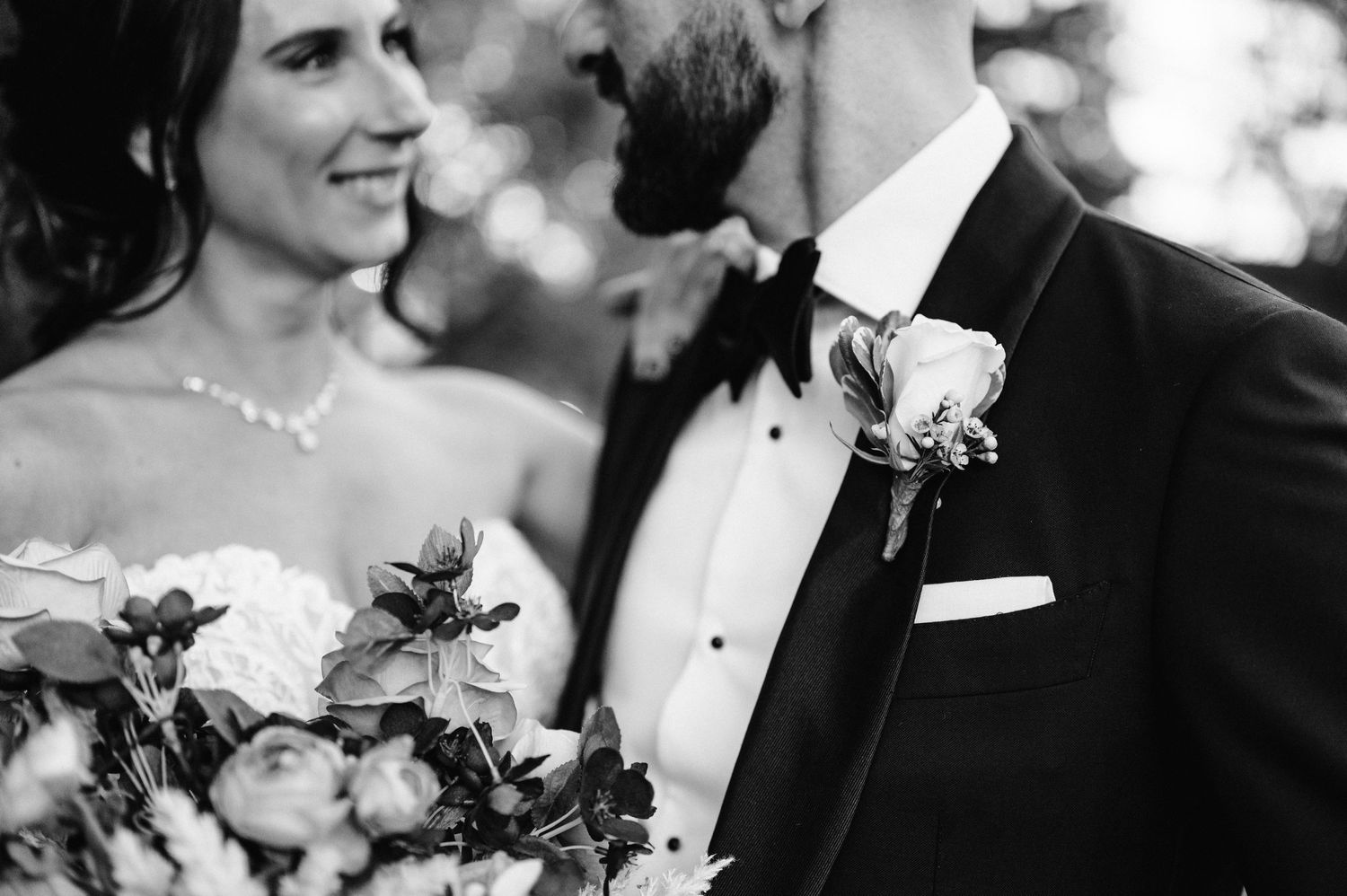 A black and white close-up of a couple on their wedding day with a bouquet of flowers.