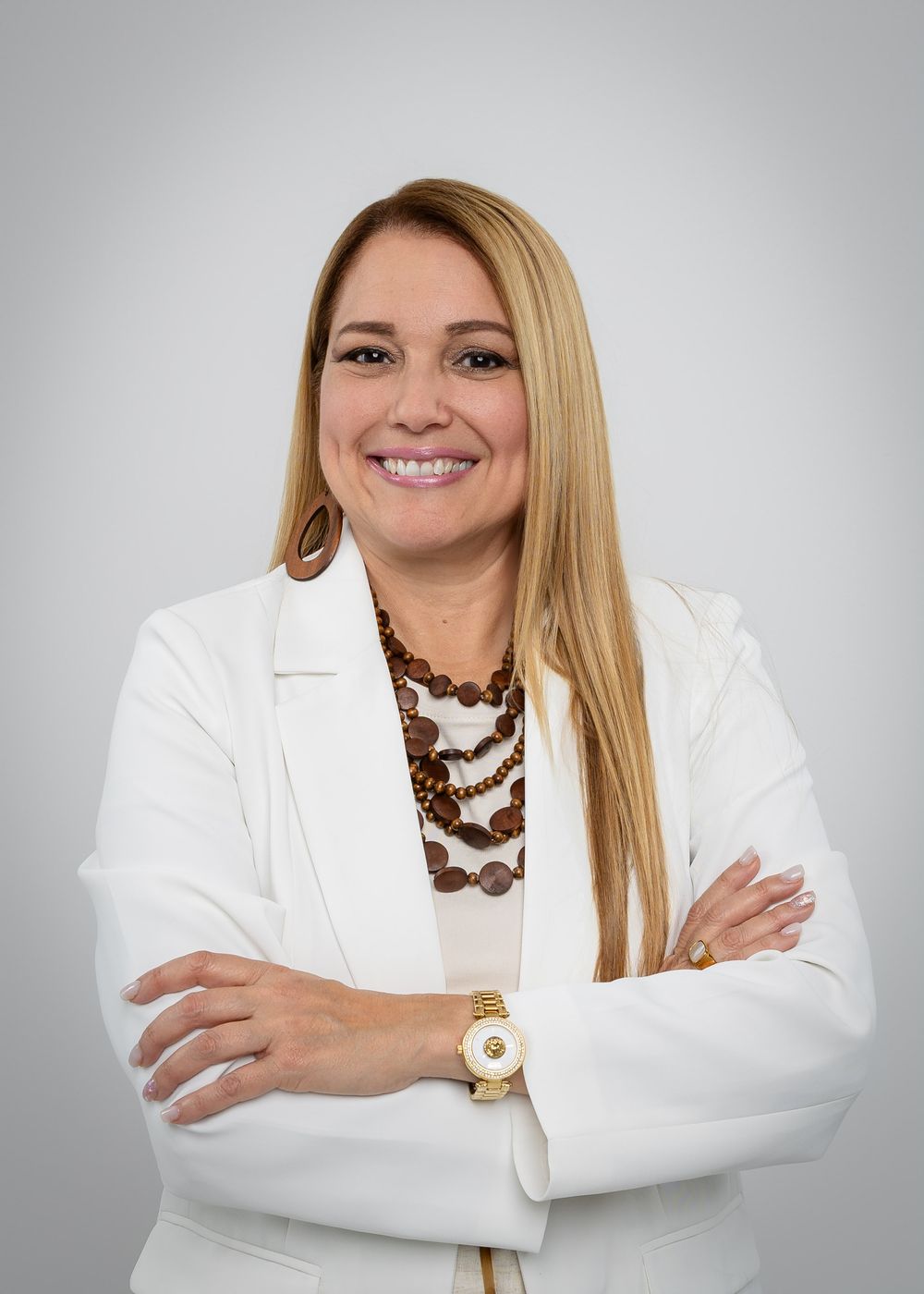 Professional headshot featuring white blazer, statement jewelry and polished appearance.