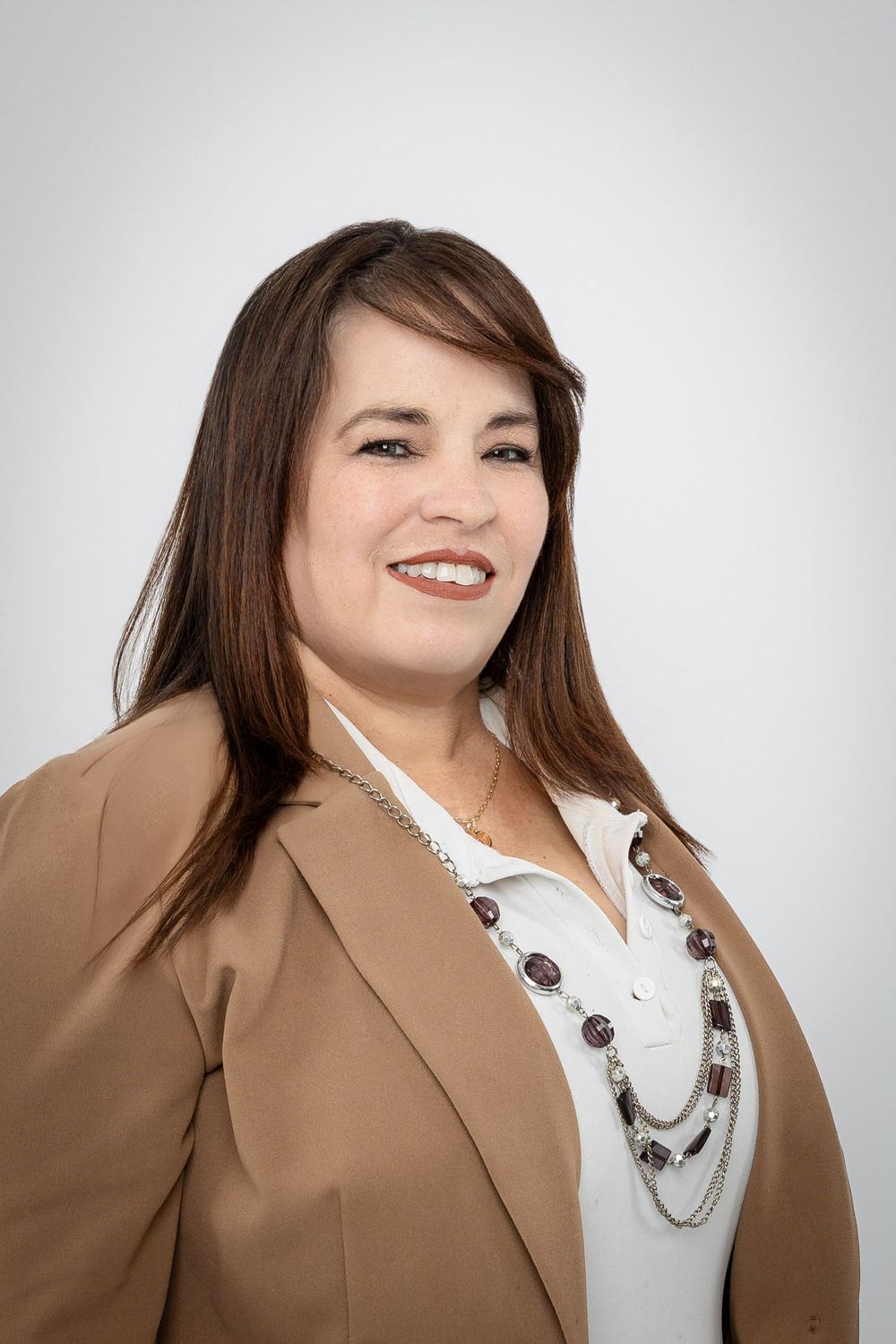 Professional portraits showing poses in tan blazer and statement necklace against light background.