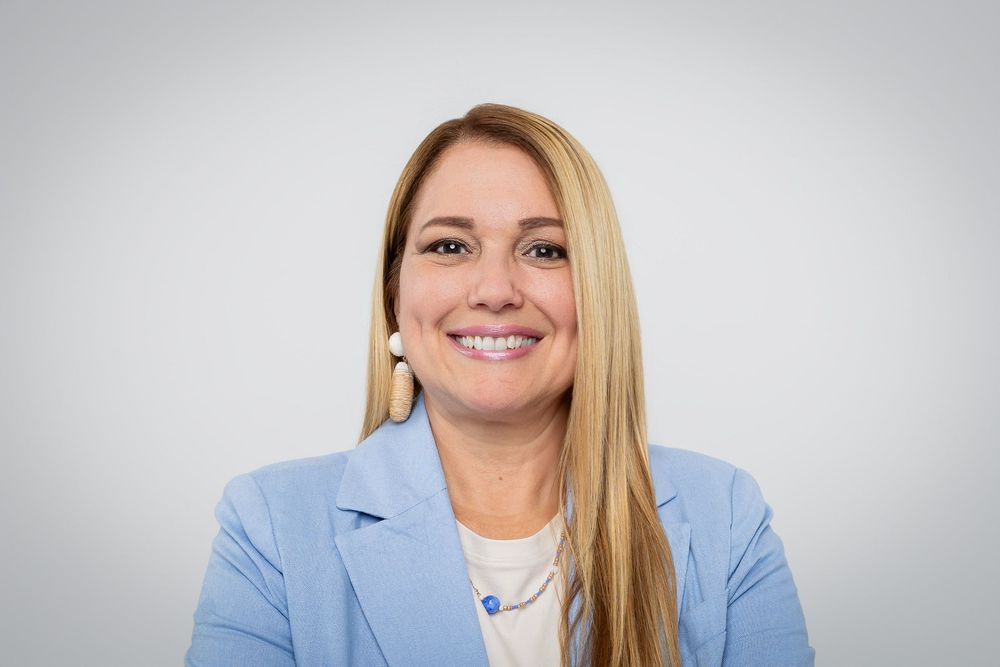 Professional portraits in light blue blazer with white top against studio background.