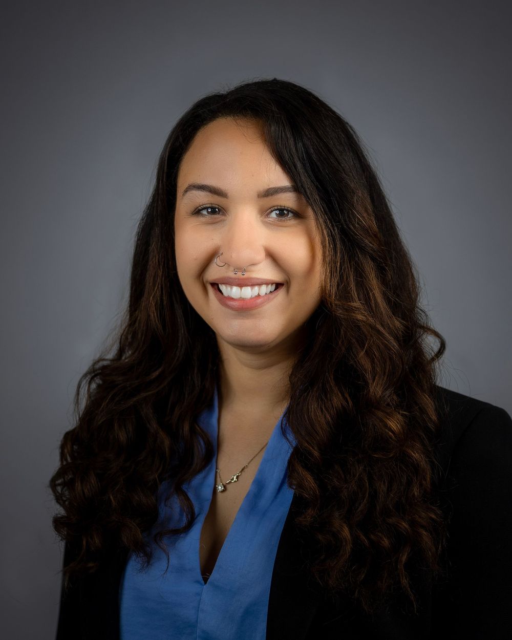 Professional headshots of woman in business attire with dark curly hair against a gray background.
