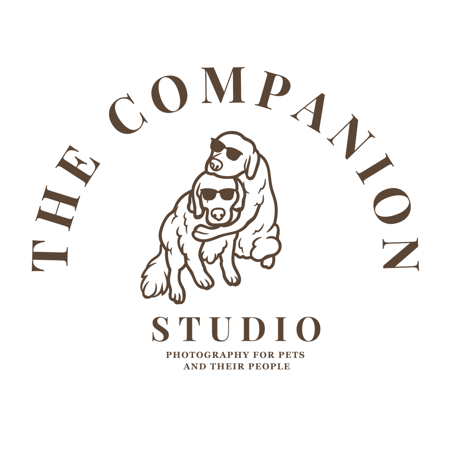 A simple circular logo design featuring two dogs sitting together in brown with text 'THE COMPANION STUDIO' around them.
