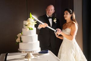 A couple cuts their elegant white wedding cake together during their reception celebration.