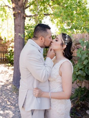 A couple shares their first kiss as newlyweds in a garden setting during their wedding ceremony.