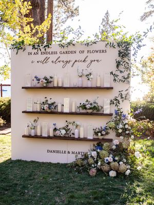 An elegant wedding seating display with floating shelves holding white vases and floral arrangements against a white backdrop.