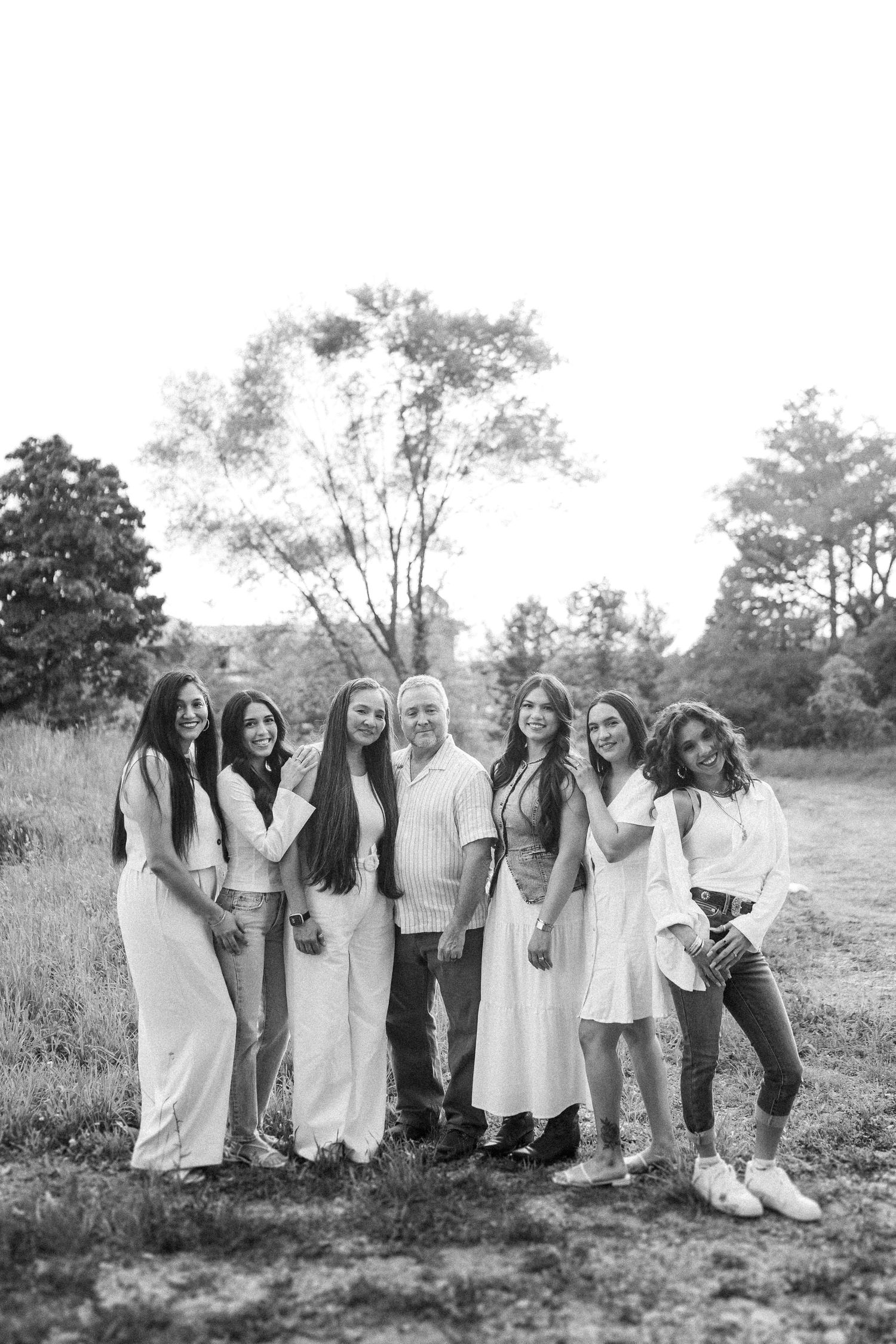 A group in coordinated white outfits poses together in a rustic outdoor setting.