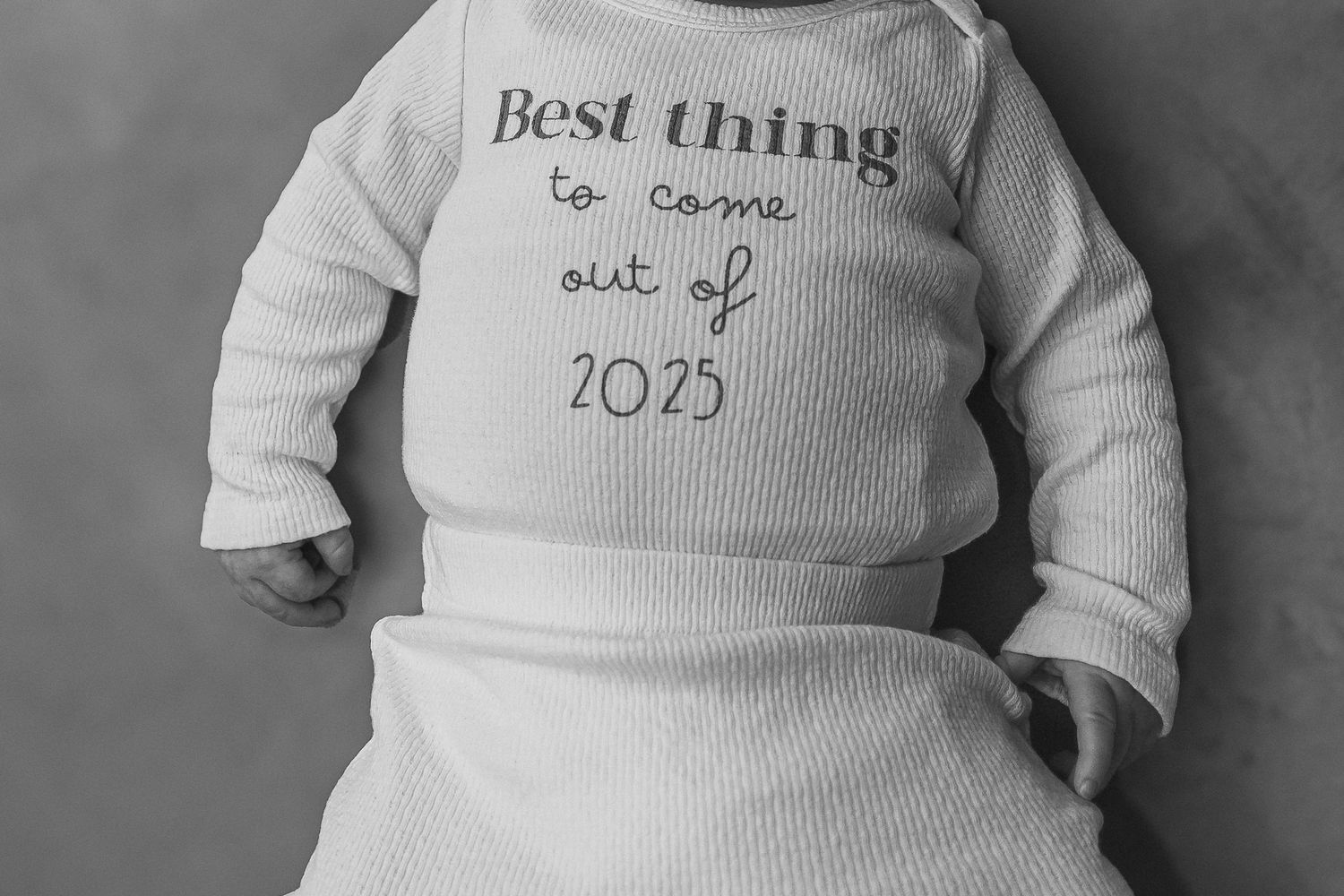 Series of black and white photos showing a baby wearing white onesies with text phrases that reveal a clever sequential message.