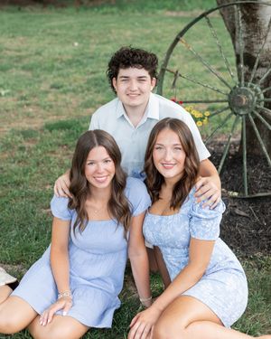 A cheerful group poses together in light blue outfits for outdoor summer photos on a grassy lawn.