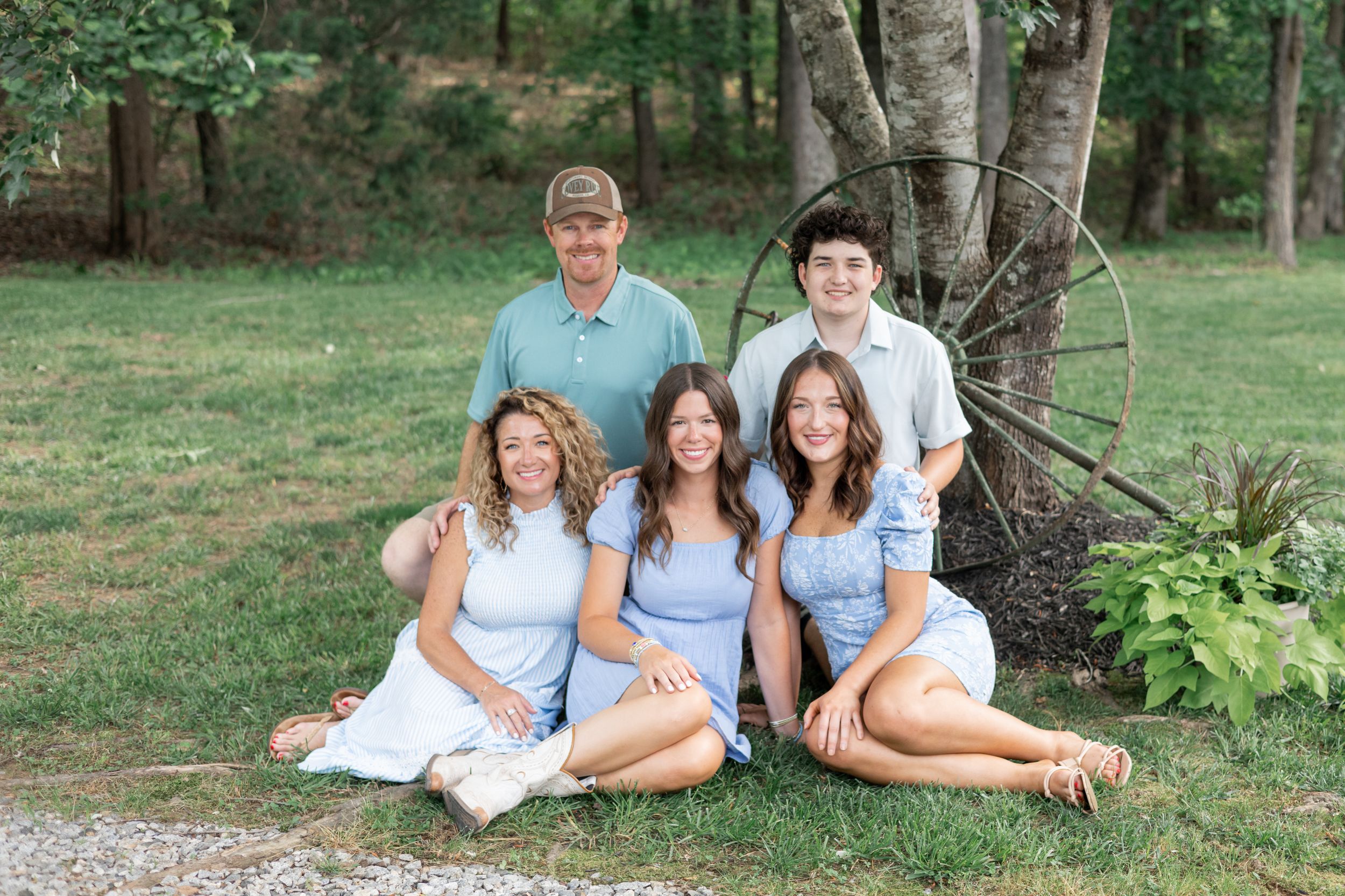 Family members gather for casual portraits under trees in coordinating blue and white outfits.
