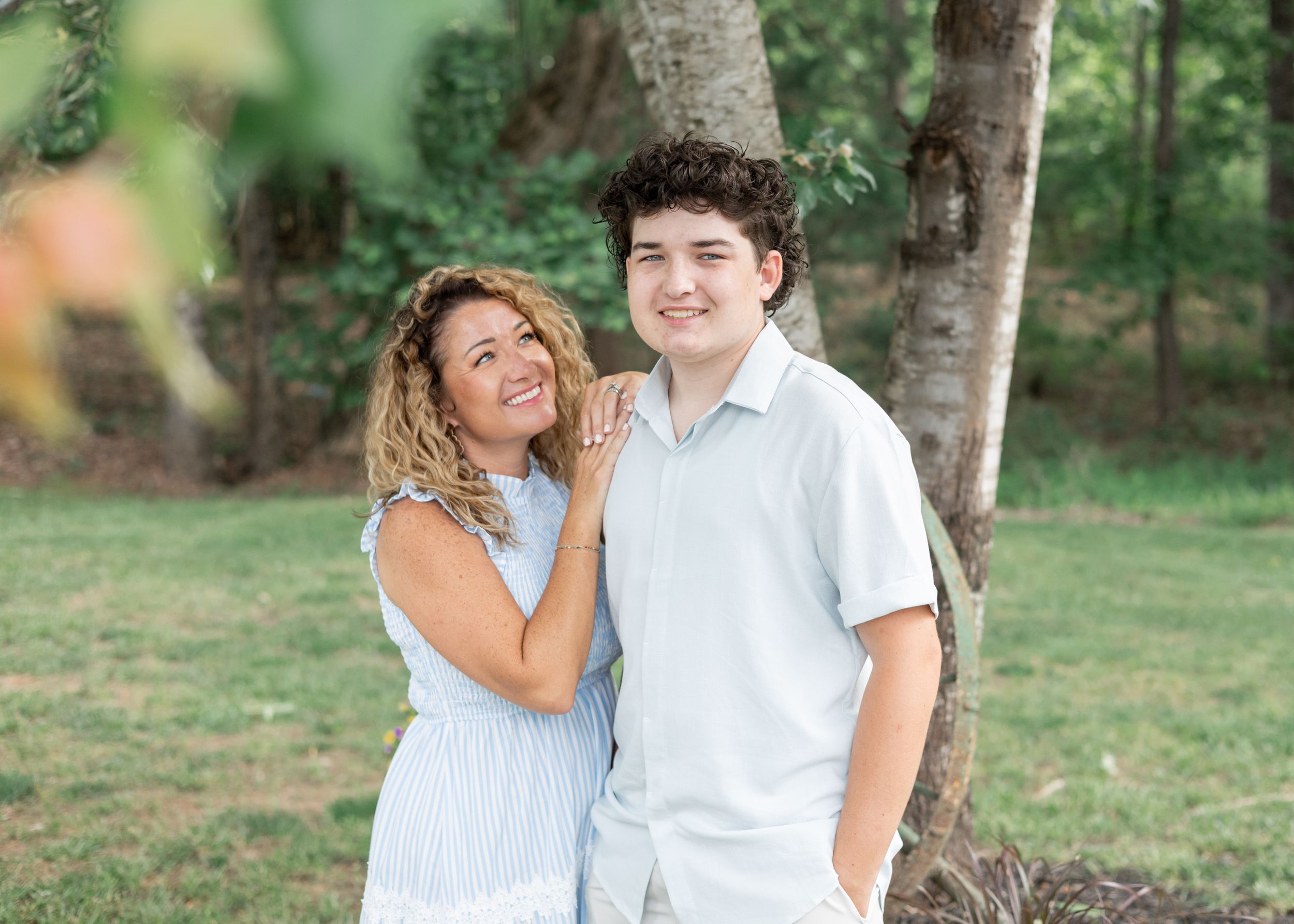 Outdoor portrait session with people wearing coordinated blue and white outfits under trees.