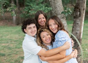 Group embraces while wearing coordinated outfits during an outdoor summer photo session.