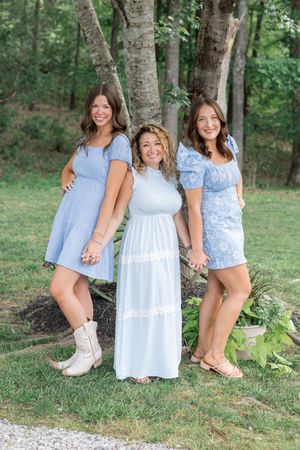 Group poses casually on grass wearing coordinated light blue and white summer outfits.