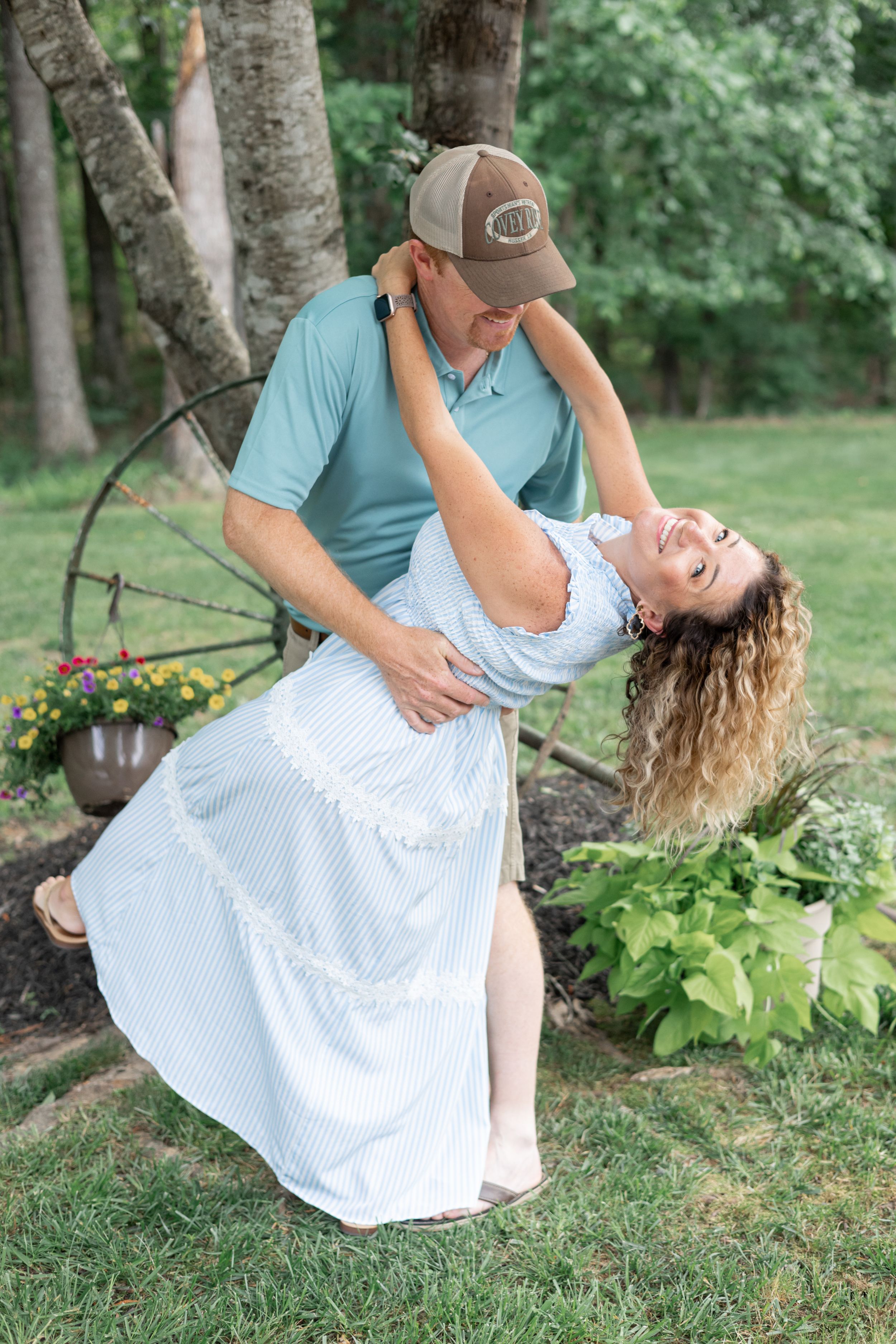 Romantic outdoor couples photo session with playful dipping poses in a garden setting.