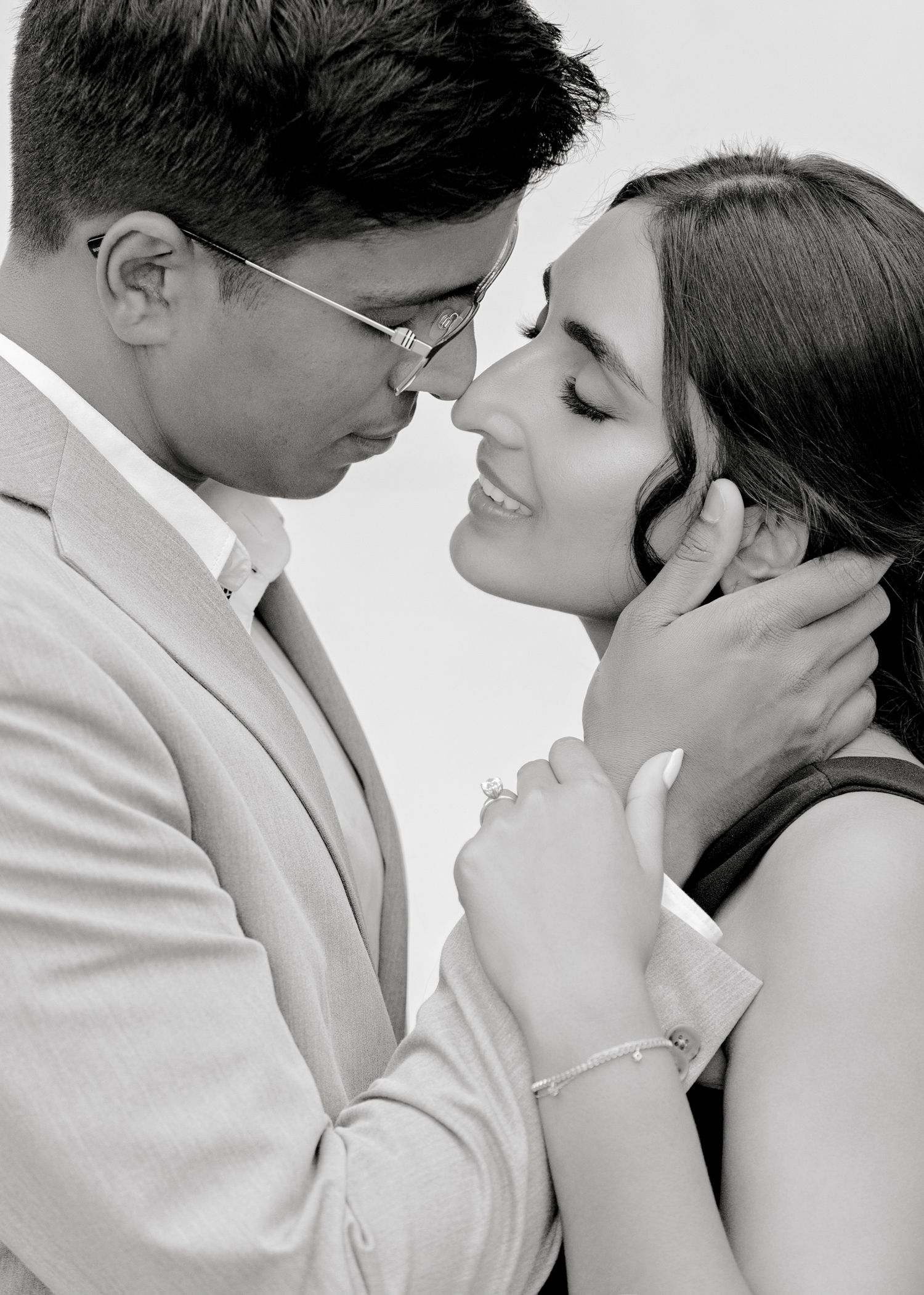 Black and white close-up shots of a tender romantic moment between formally dressed couple against a white background.