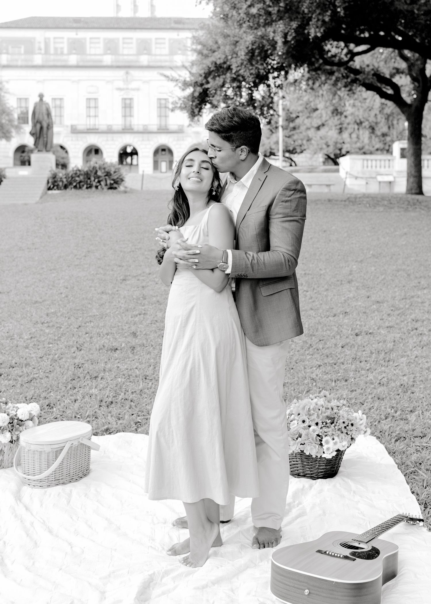 Black and white photos of romantic picnic scene with couple in flowing dress and suit on grass.