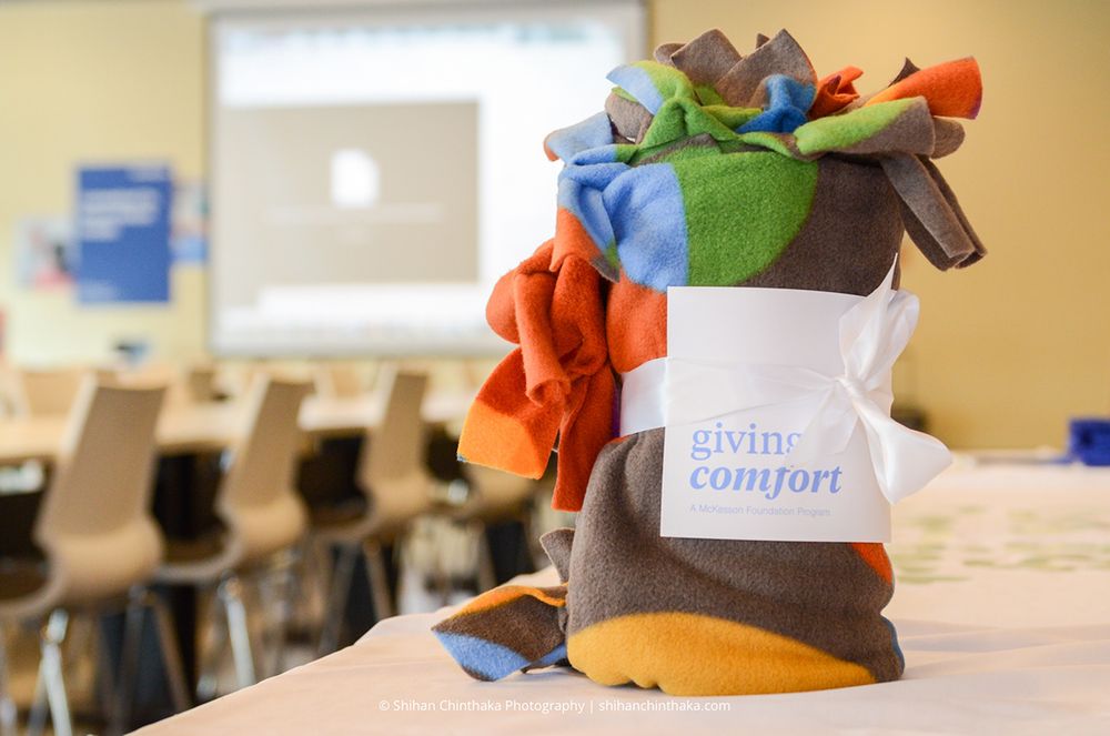 Basket labeled 'giving comfort' filled with colorful plush toys sits on desk.