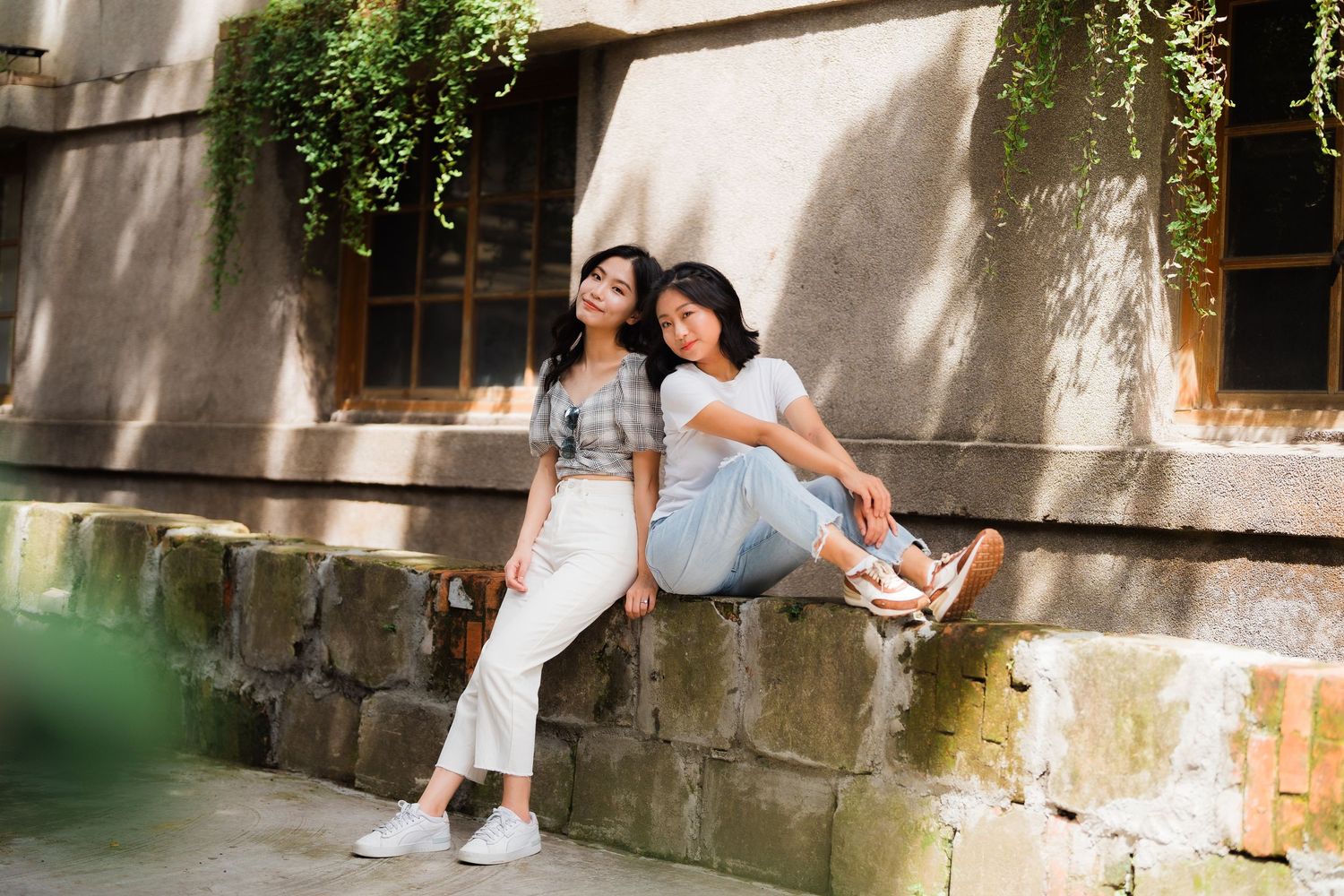 Couple walking together along a waterfront pier on a sunny day wearing casual summer attire.