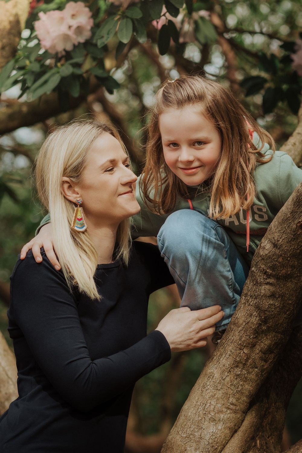 Joyful candid sequence of mother and child sharing playful interactions while leaning against a tree trunk in nature.
