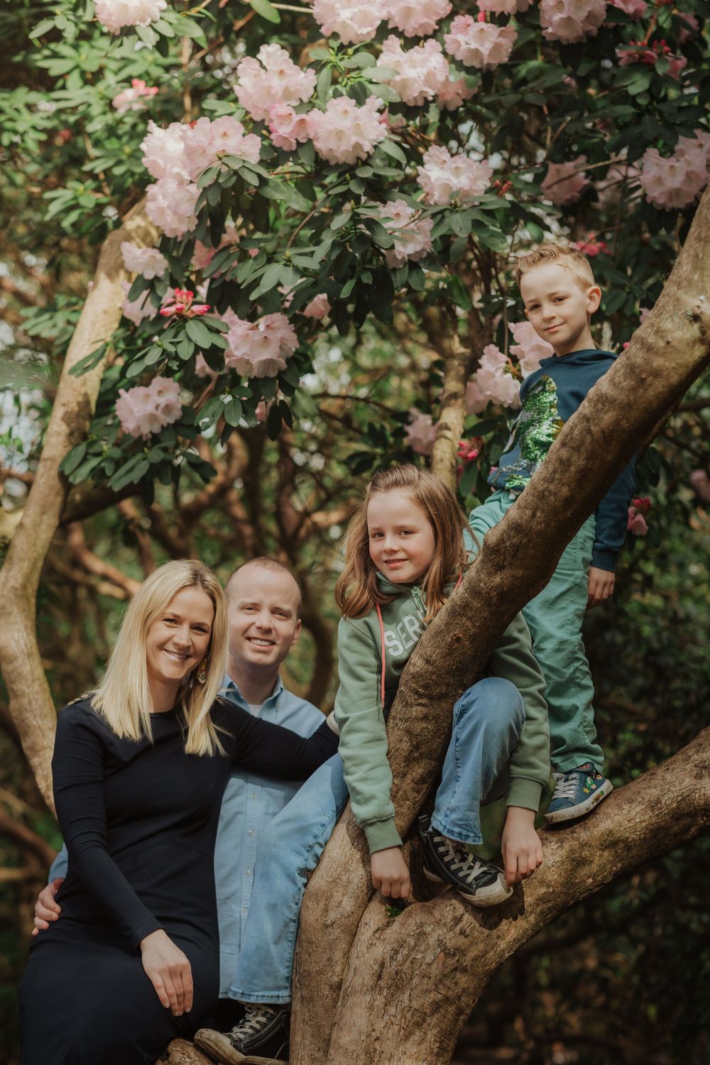 Loving family spends quality time together under blooming pink cherry blossoms in springtime garden setting.