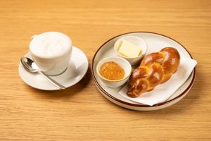 Freshly baked croissant served on a white plate against a warm wooden table surface.