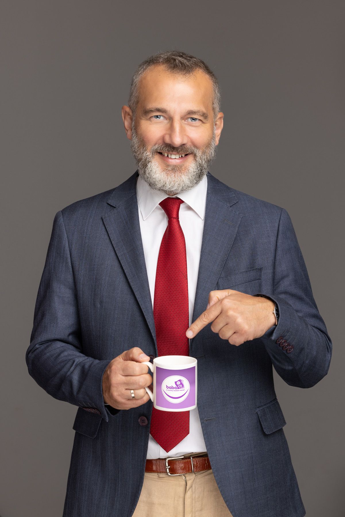 Professional in navy suit and red tie points to and interacts with a smiling coffee cup in a series of poses against gray backdrop.
