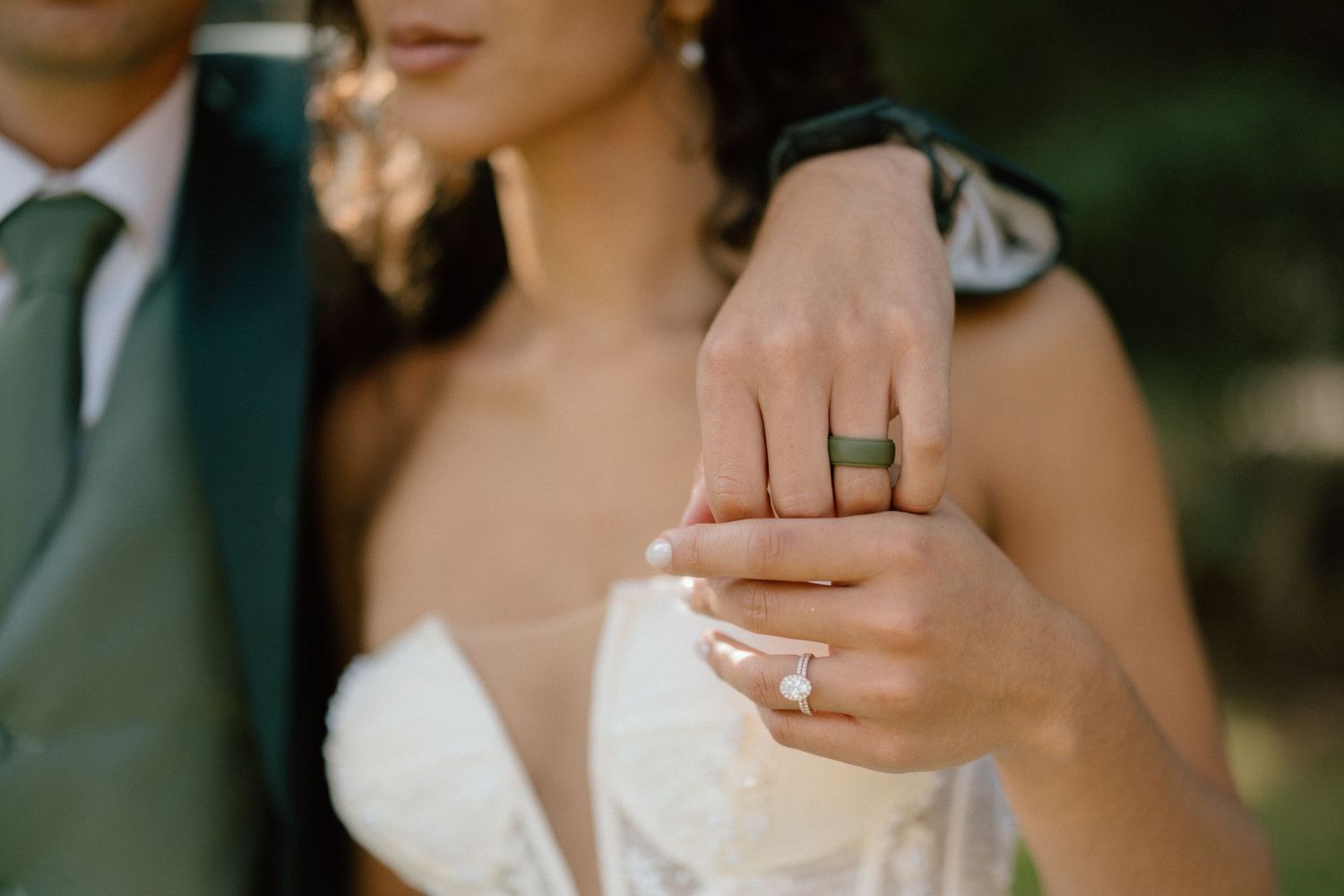 Close-up of wedding rings and hands in elegant bridal attire.