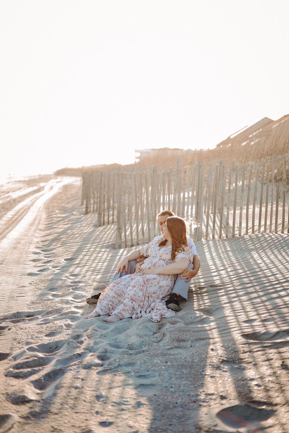Pregnant mother sitting on a sandy beach path at golden hour during a maternity session in Havelock North Carolina.