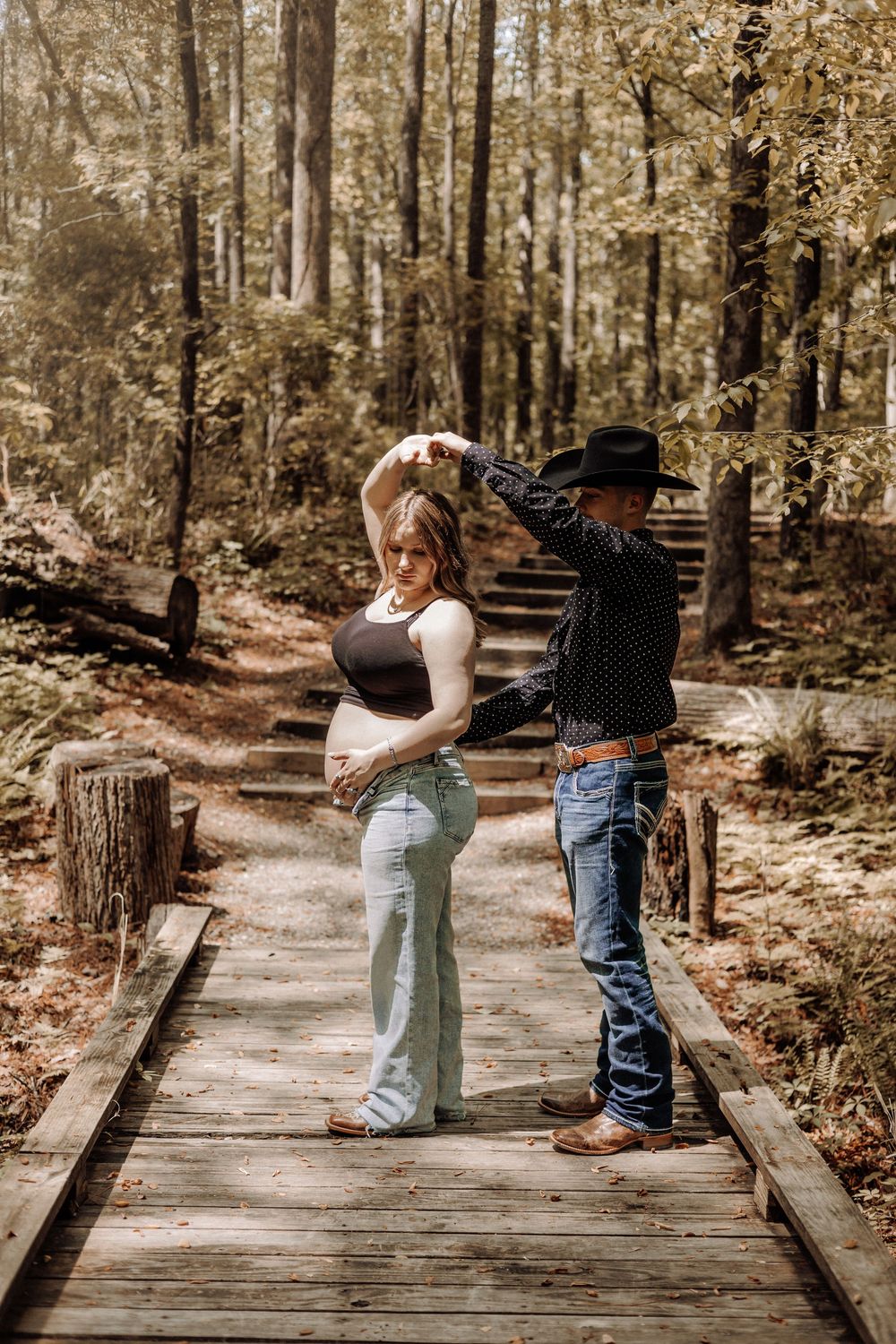 North Carolina maternity photographer — couple standing on a forest boardwalk during a warm, golden sunset session.