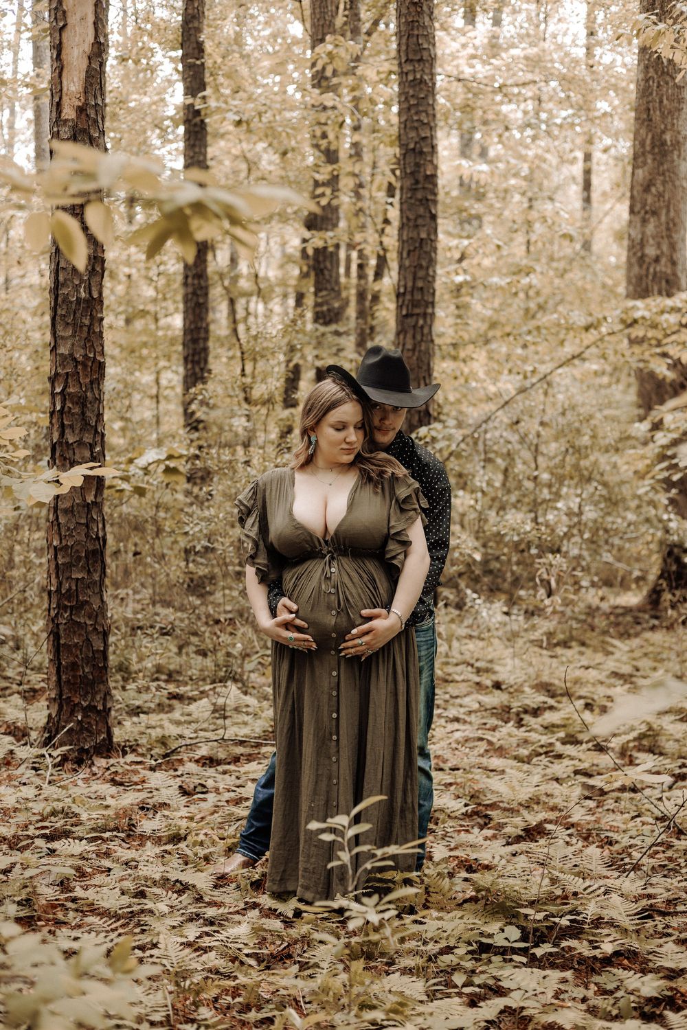 Havelock NC maternity photographer — expecting mother standing in an autumn forest with warm golden lighting.