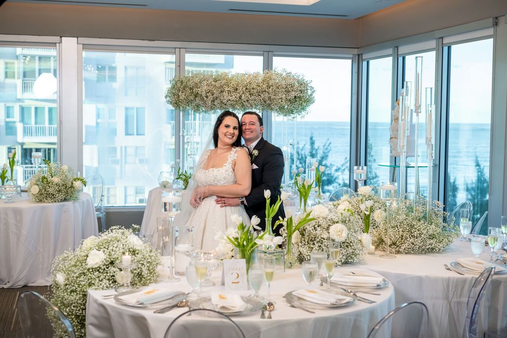 A wedding reception with panoramic city views and white floral decorations.
