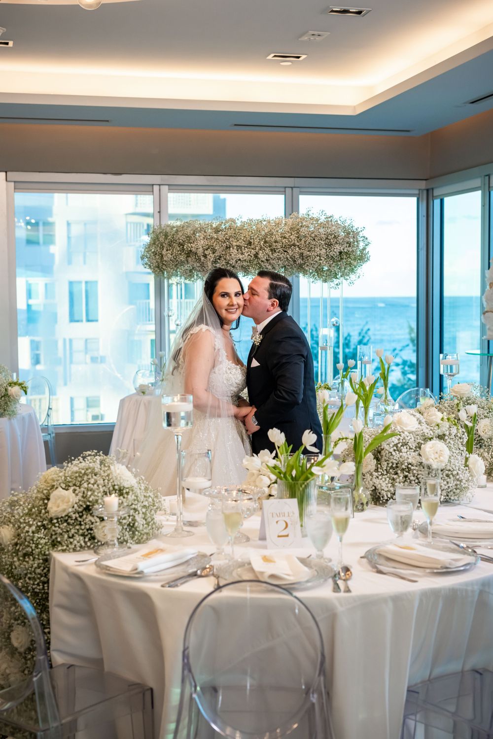 A wedding celebration in a bright venue with suspended floral arrangements and modern decor.