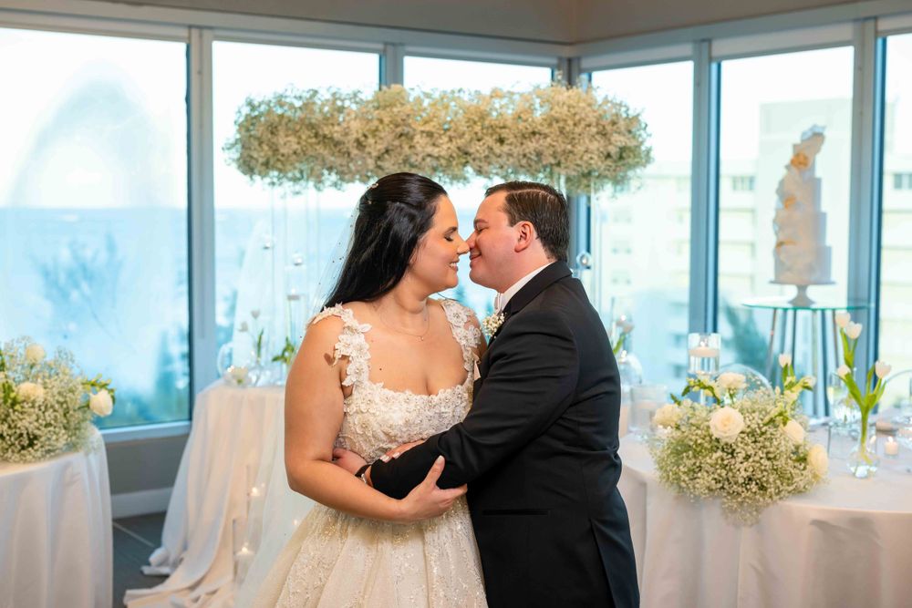 Romantic moment between couple in wedding attire with floral crown decoration overhead.