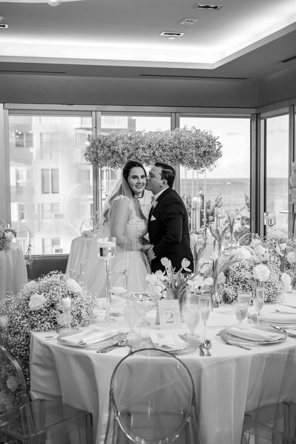 Black and white photo of a wedding reception with elegant table settings and floral decor.