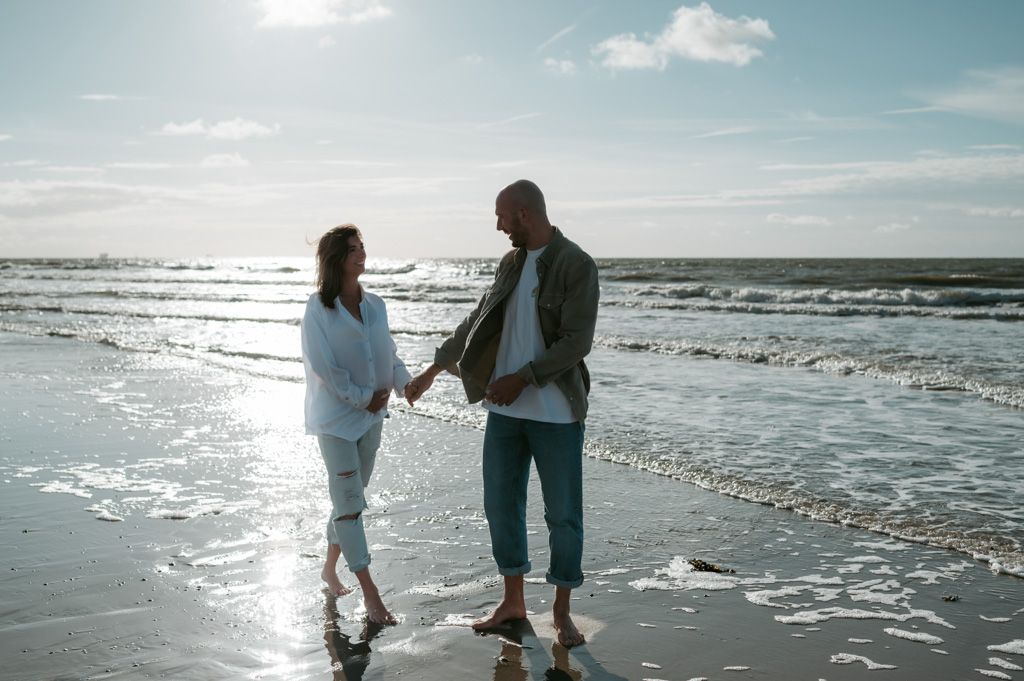 Melissa Stuer Photography Moederschapsfotograaf Moerbeke Zwangerschapsfotograaf koppel die handen vasthouden wandelend op het strand aan zee