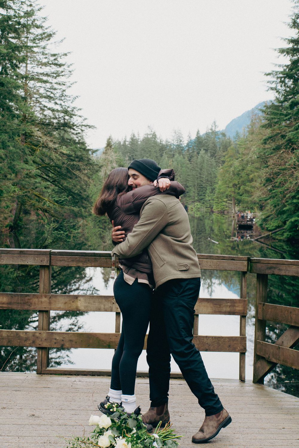 An emotional celebration moment between two people on a scenic forest overlook.
