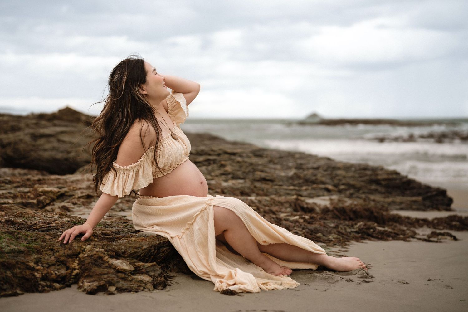 Artistic maternity boudoir photo of expecting mother in white robe and lingerie.