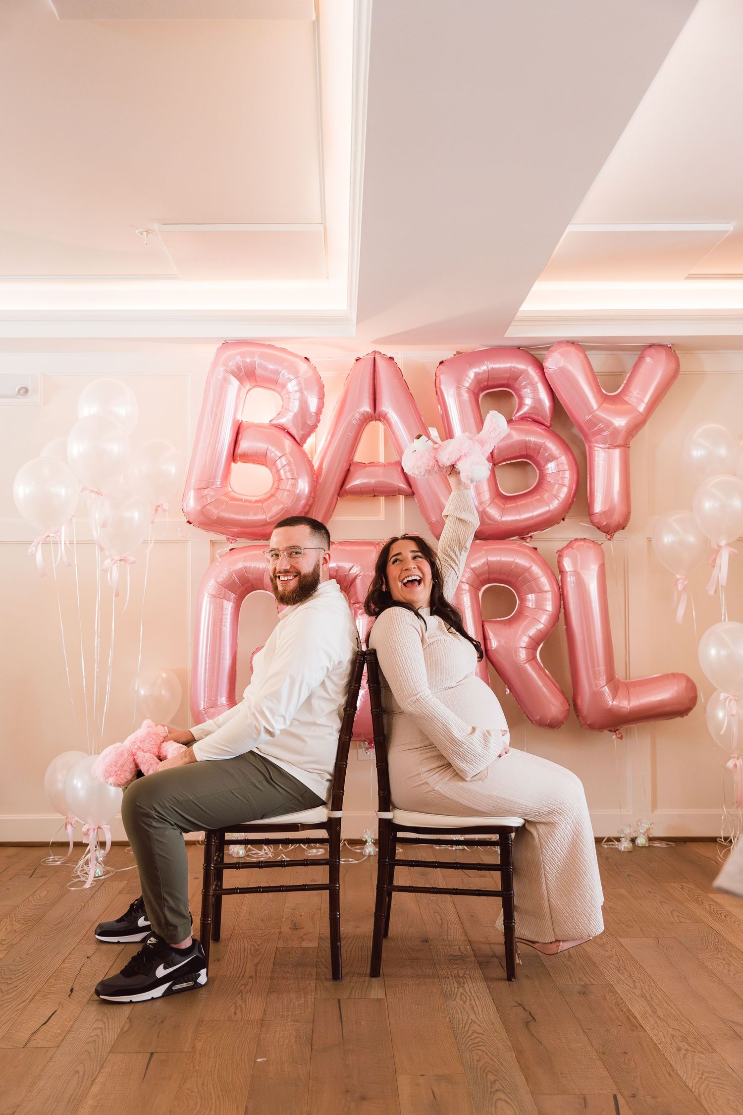 Baby shower in Derry, New Hampshire with happy expecting couple playing games in pink outfits for their baby girl.