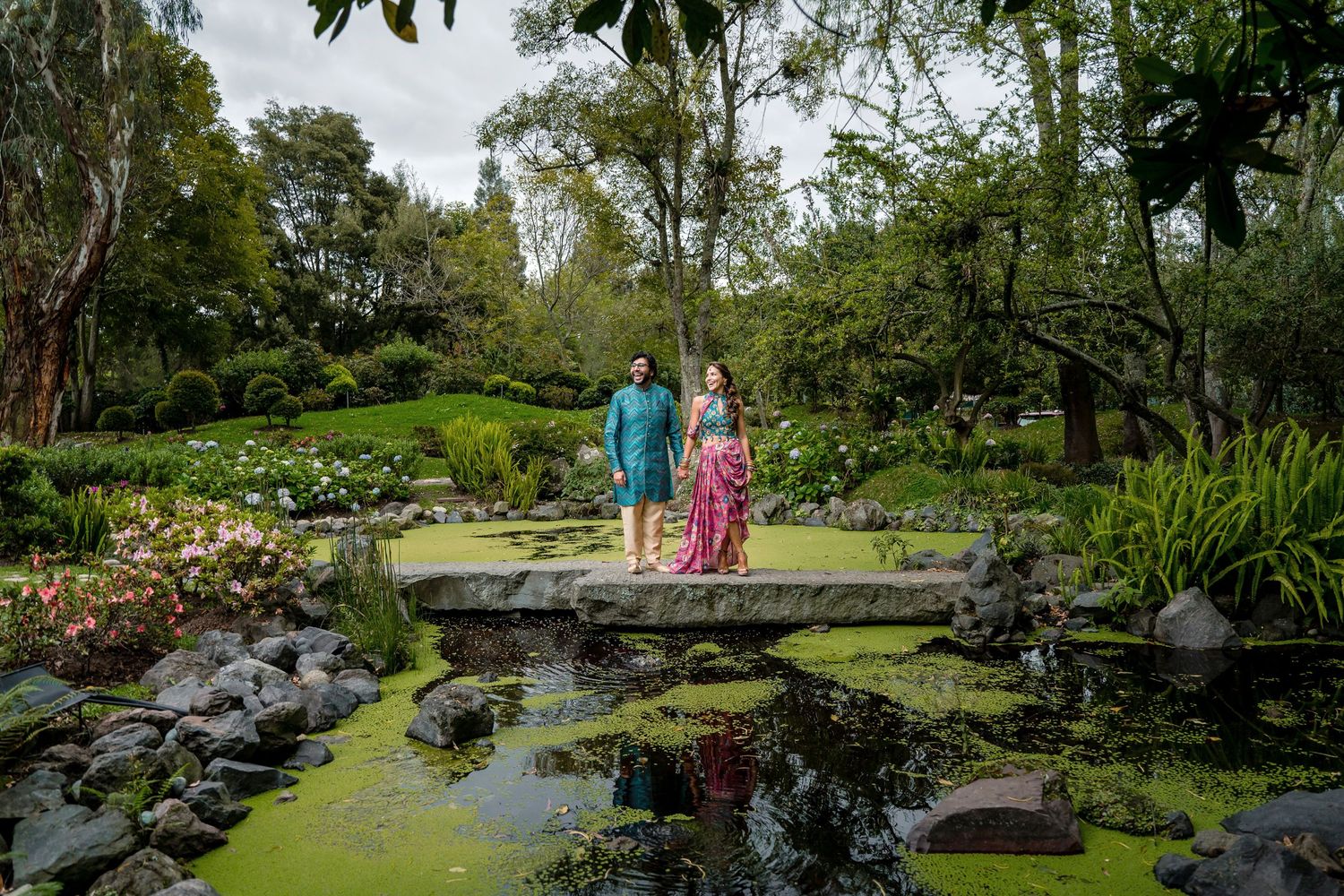 Serene garden landscape with a tranquil pond surrounded by lush greenery and stone features.
