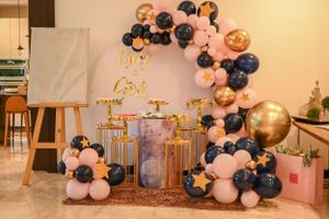 Elegant party setup with balloon arch, gold decorations, and dessert table for a festive celebration.