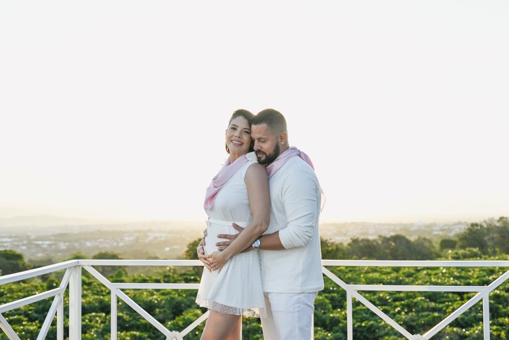 A loving couple embraces on a balcony overlooking rolling hills during golden hour.