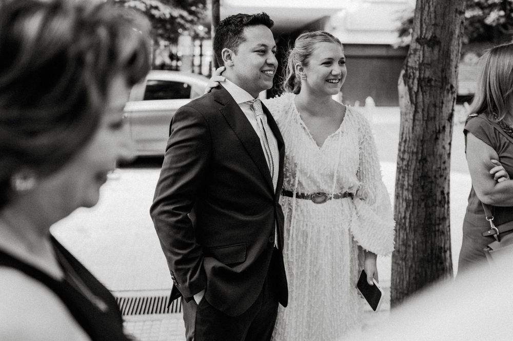 A couple stands together outdoors in formal wedding attire sharing a candid moment.