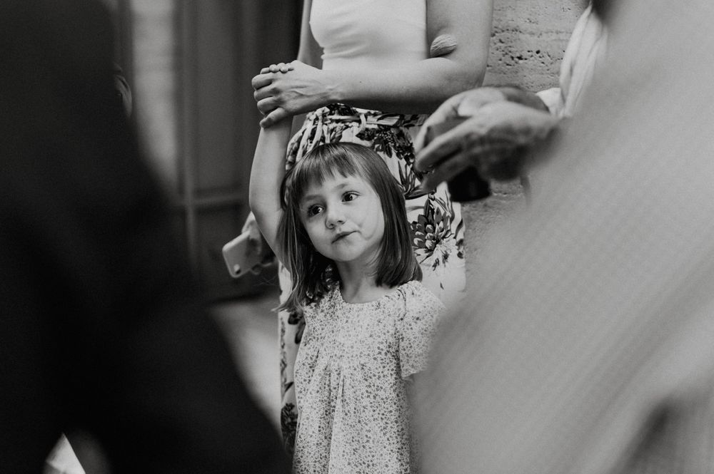 A young child in a sparkly dress watches a celebration unfold with a curious expression.