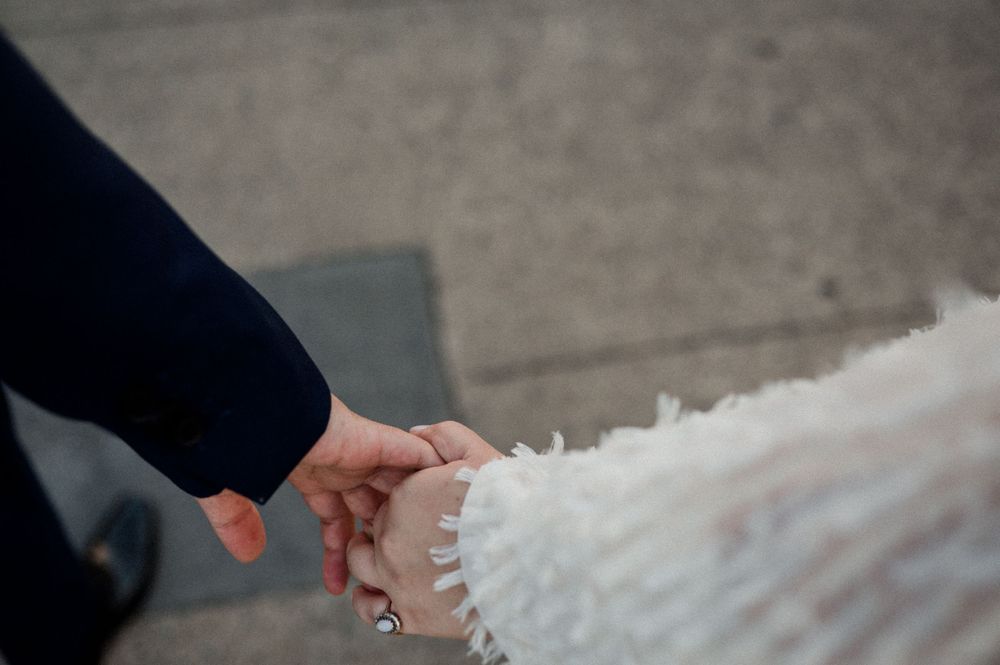 A close-up shot of hands holding each other during a winter wedding ceremony.