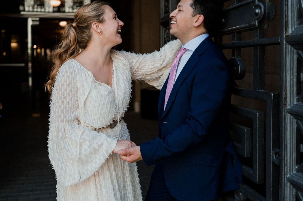 A candid moment of laughter shared between a couple by an ornate doorway.