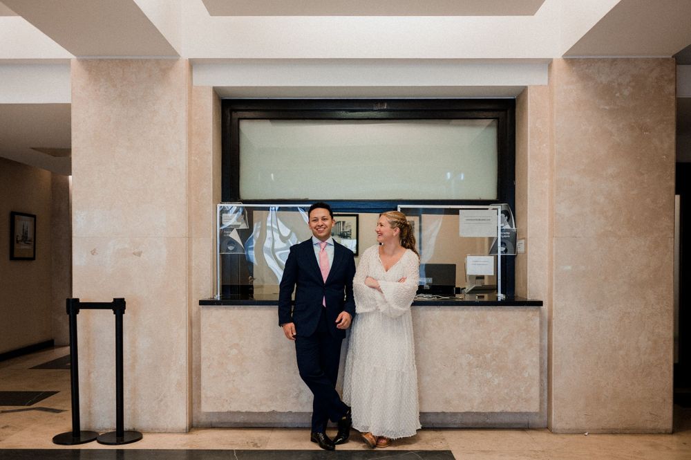 A couple walks together through an elegant lobby area in formal wedding attire.