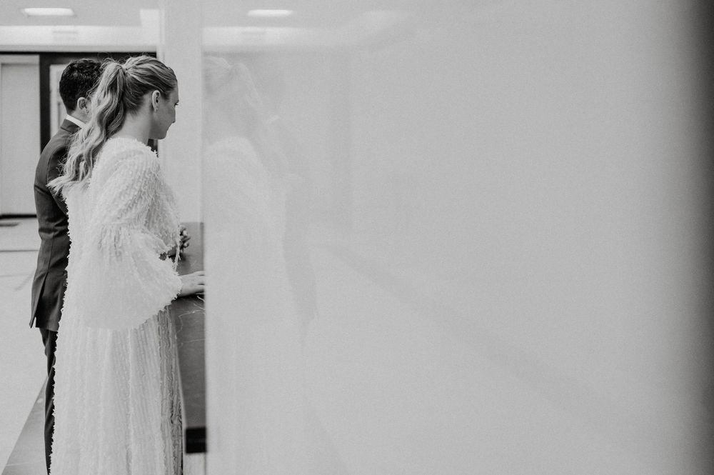 A side view of someone in a flowing white wedding dress standing near a wall.