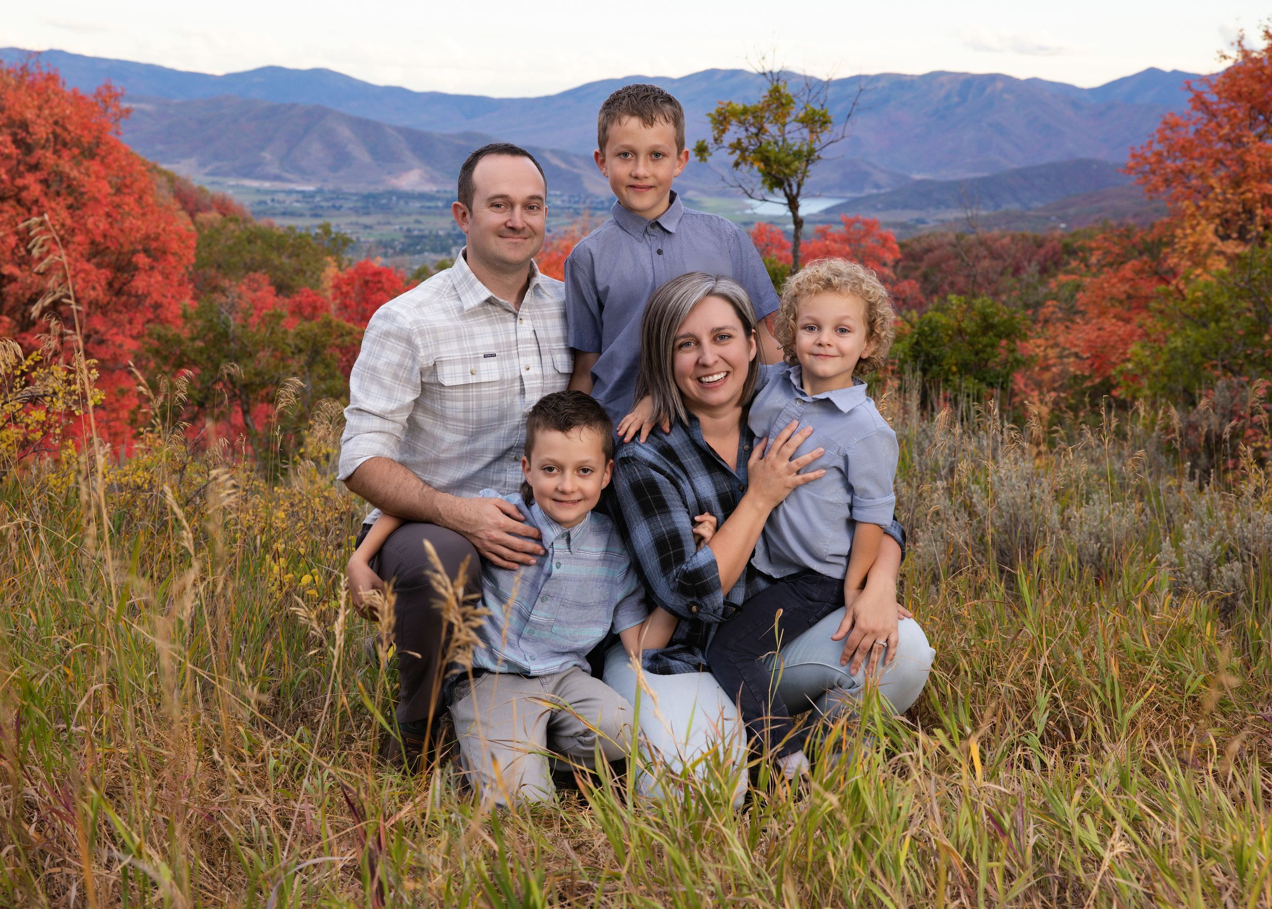 Family enjoying a scenic autumn mountain view with colorful fall foliage in the background.