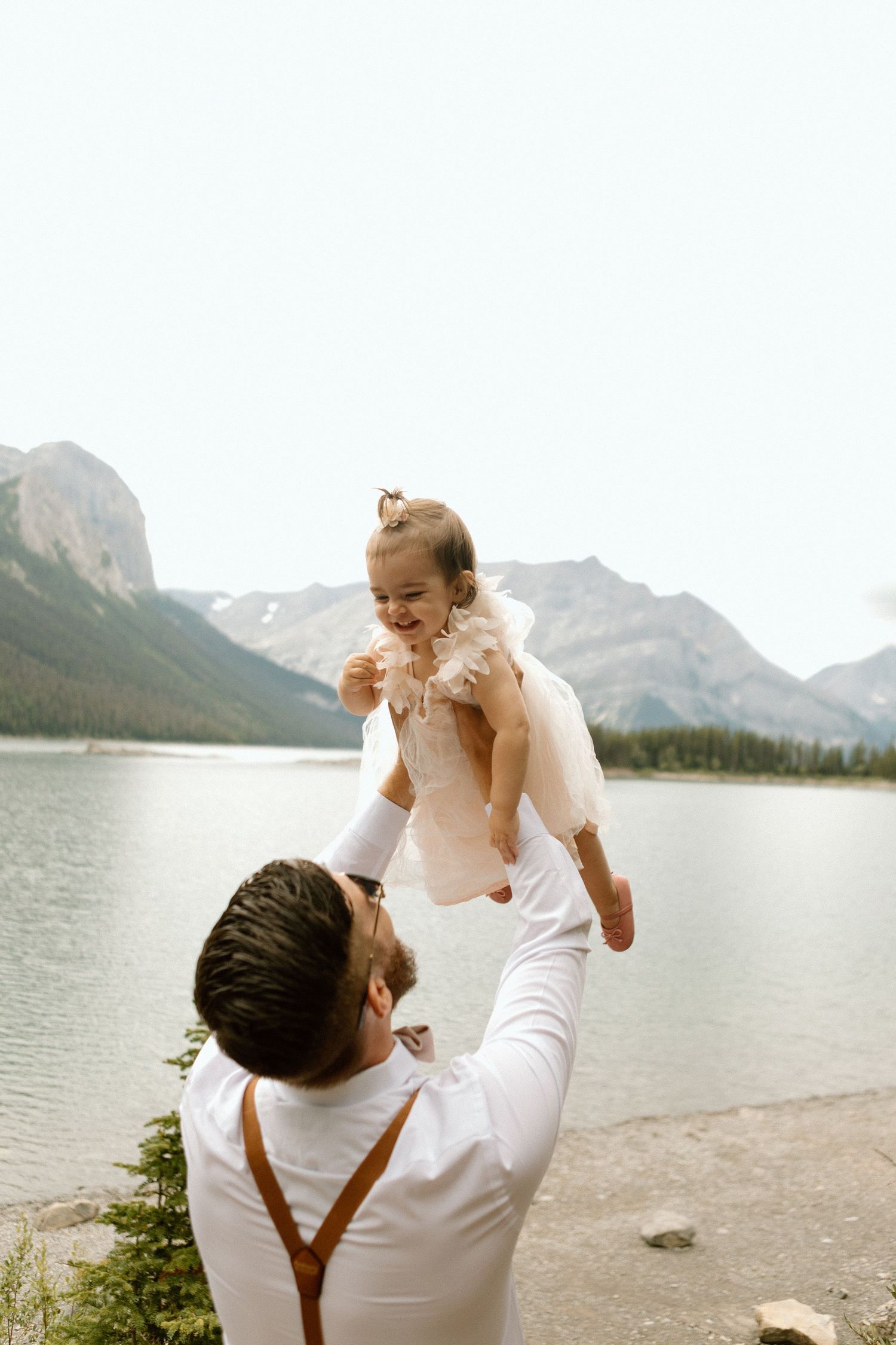 A tender moment between a couple against a mountain lake backdrop.